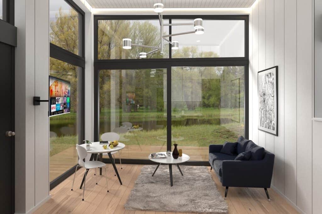 Ett rum med stora fönster med tv och bord från Attefallhus 30 kvm modell Louise