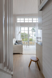 interiör attefallshus med helt vit inredning och utsikt ut genom spröjsade glasdörrar